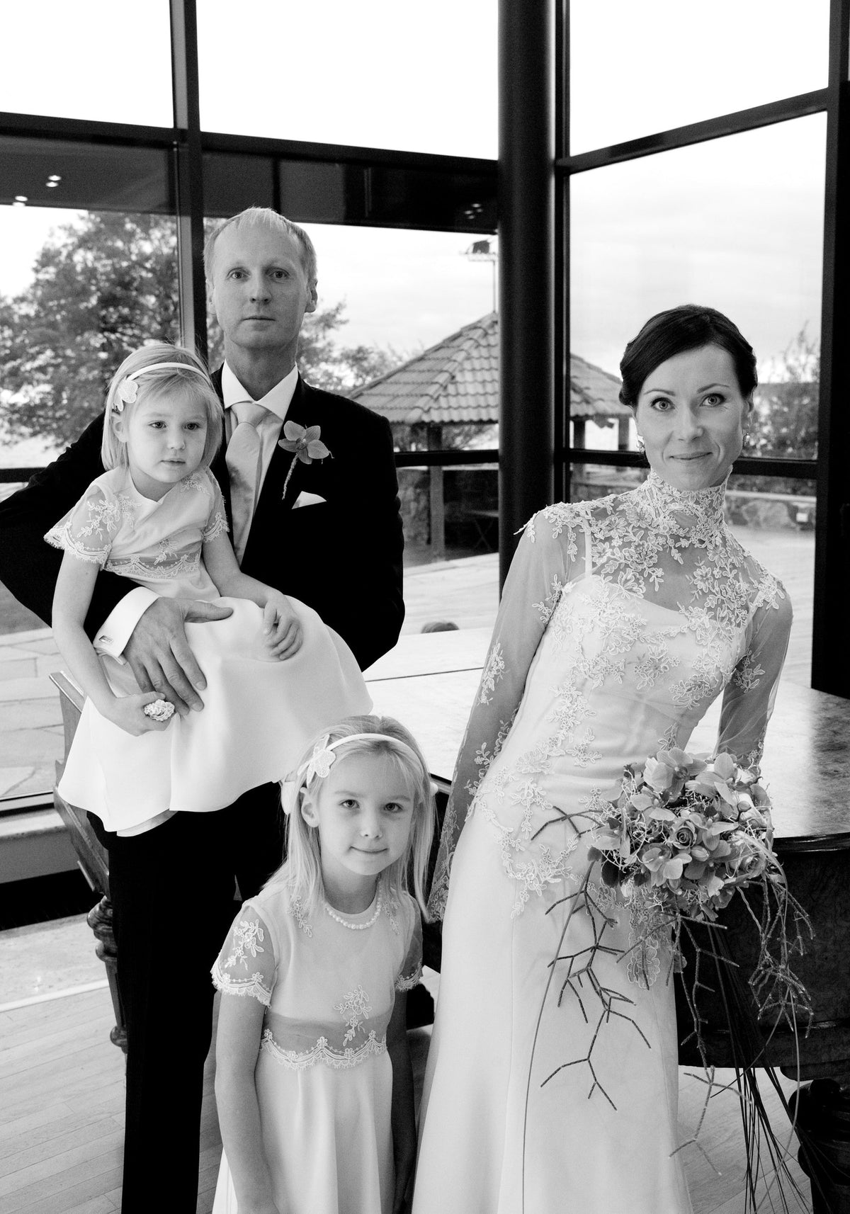 Pruut kõrge kaeluse ja liibuva pitspihikuga kleidis perekonna pulmafotol